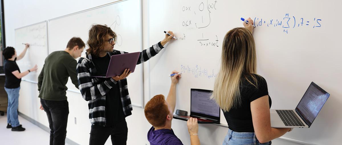 students writing equations on whiteboard